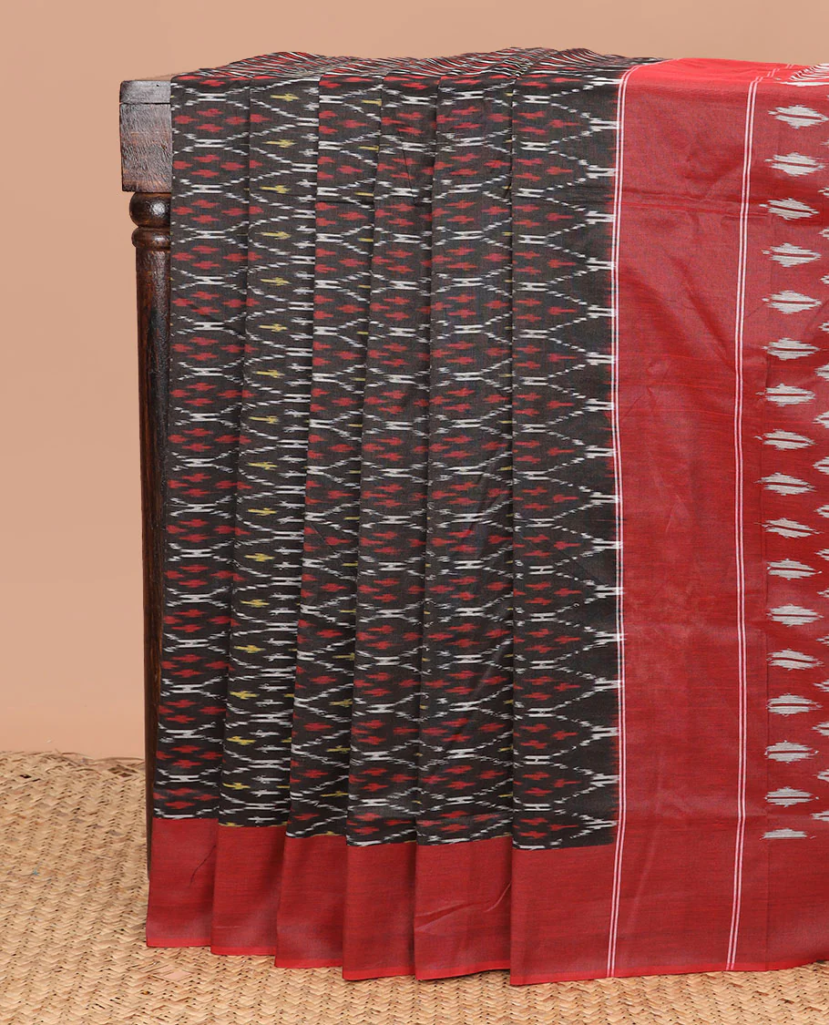 Black Ikkat Cotton Saree Adorned with Ogee Patterns in Ikkat Weave, Complemented by a Contrast Plain Border, and Pallu Steeped with Ikkat Buttas