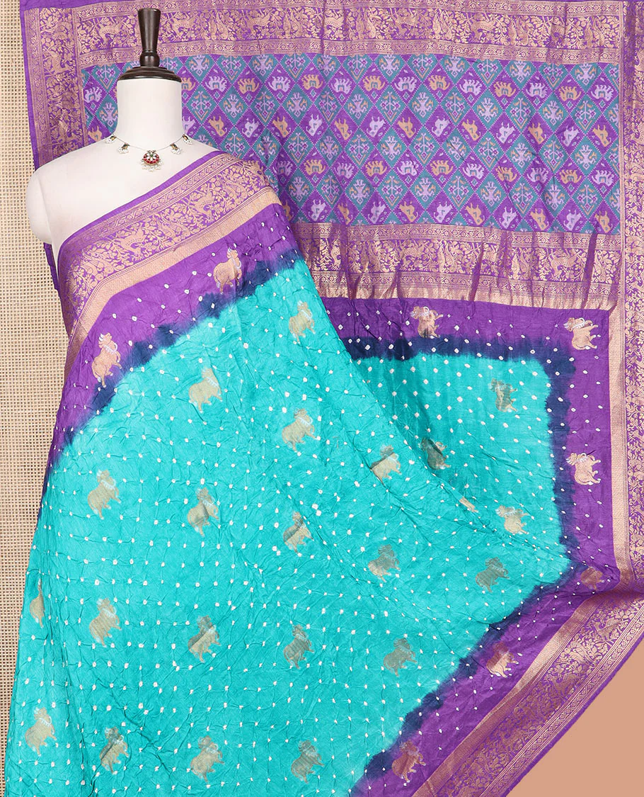 Blue bandhani dots and Pichwai cow motifs bandhani silk saree, contrast Pichwai cow and animal motifs zari border, and patola-style butta enclosed jaal pallu