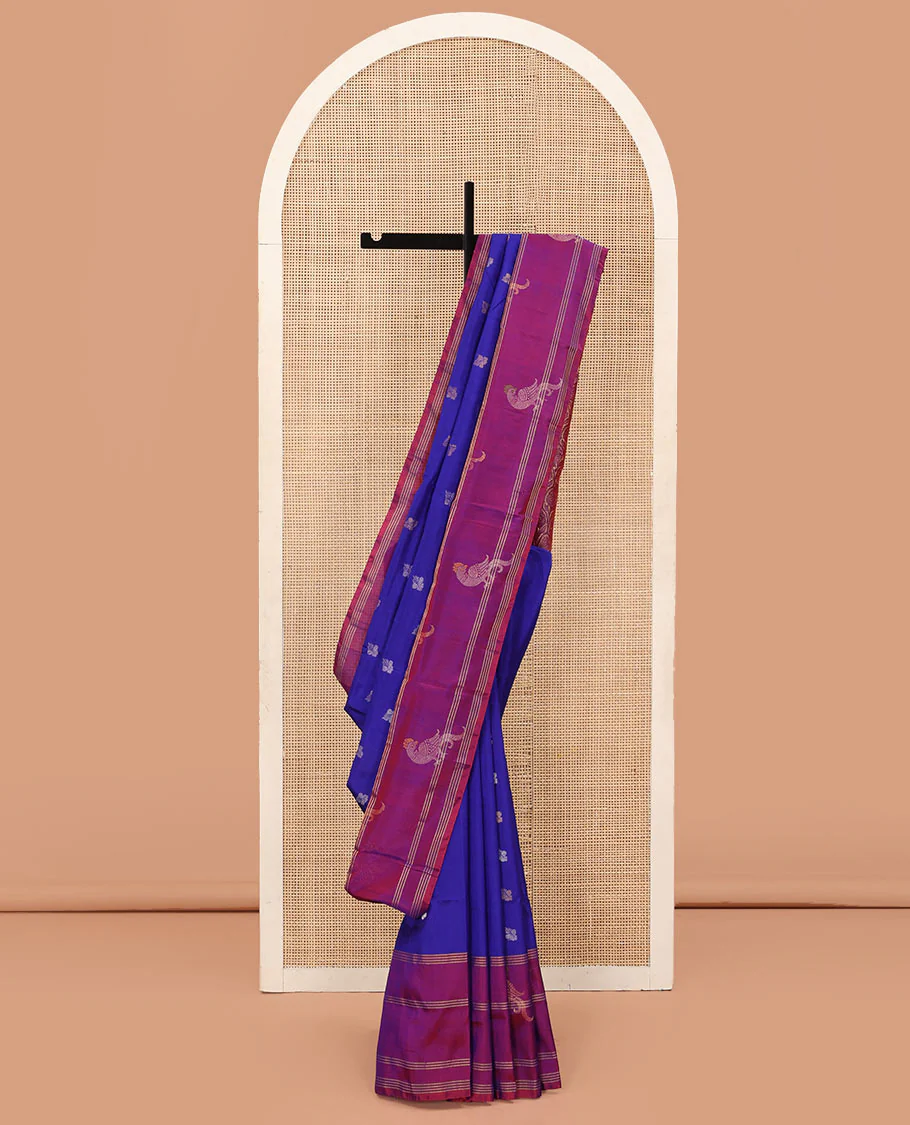 Blue Uppada Silk Saree Enlivened With Zari Buttas, Captivating Contrast Border Featuring Zari Stripes And Peacock Motifs, Pallu Depicting Rose Flower-Enclosed Mughal-Style Arches, And Paired With A Contrast Blouse