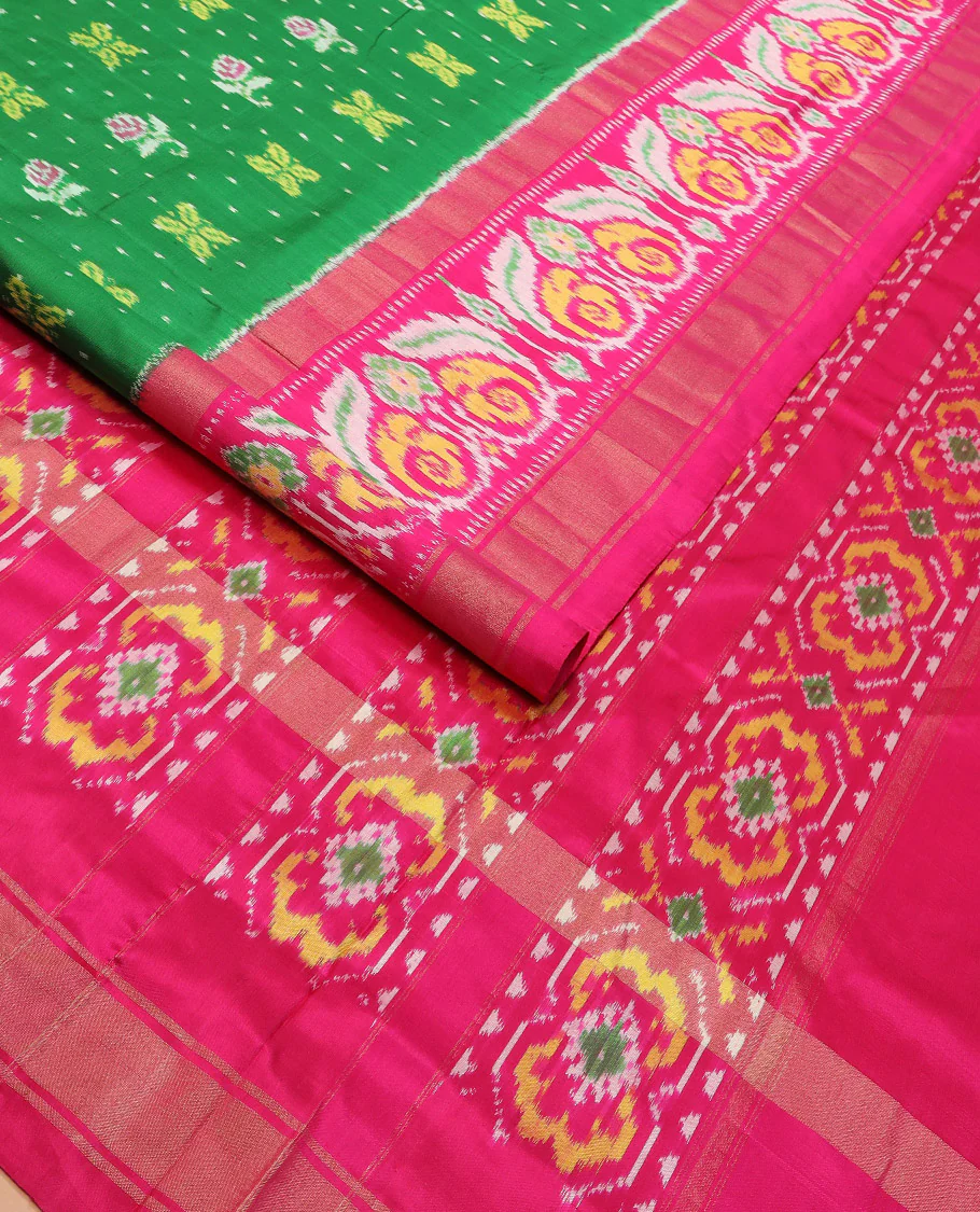 Green Ikkat silk saree features floral Ikkat buttas, highlighted with a contrast Ikkat woven border, a hazily woven Ikkat patterned pallu, and a contrast blouse