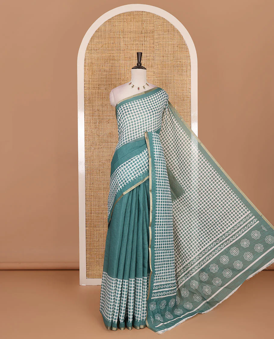 Green plain and polka dots printed linen cotton saree with piping zari border, floral-geometric print pallu, and contrast flower buttas printed blouse