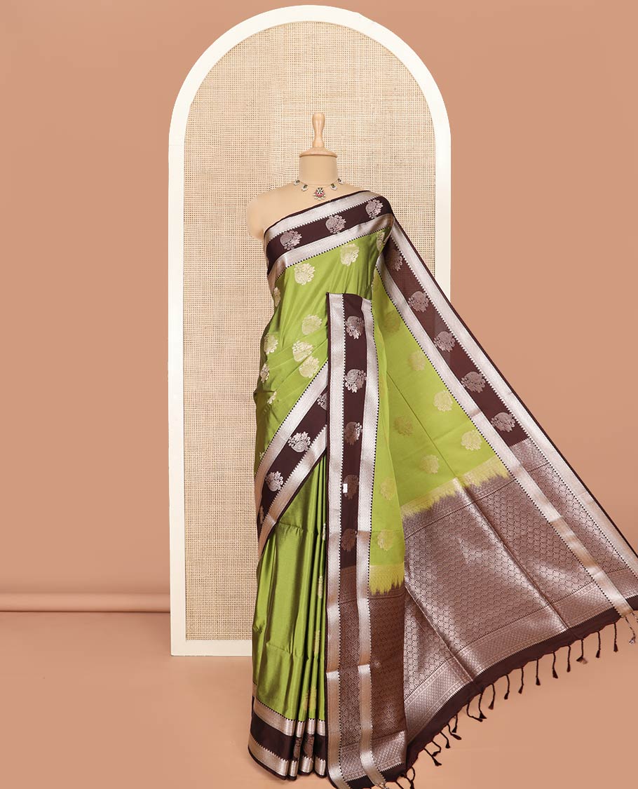Green Semi-Soft Silk Saree Enriched with Floral Zari Buttas, Complemented by Contrast Traditional Zari Border Featuring Floral and Peacock Feather Motifs, Pallu Intricately Designed with Jaal Designs, and Paired with a Contrast Blouse