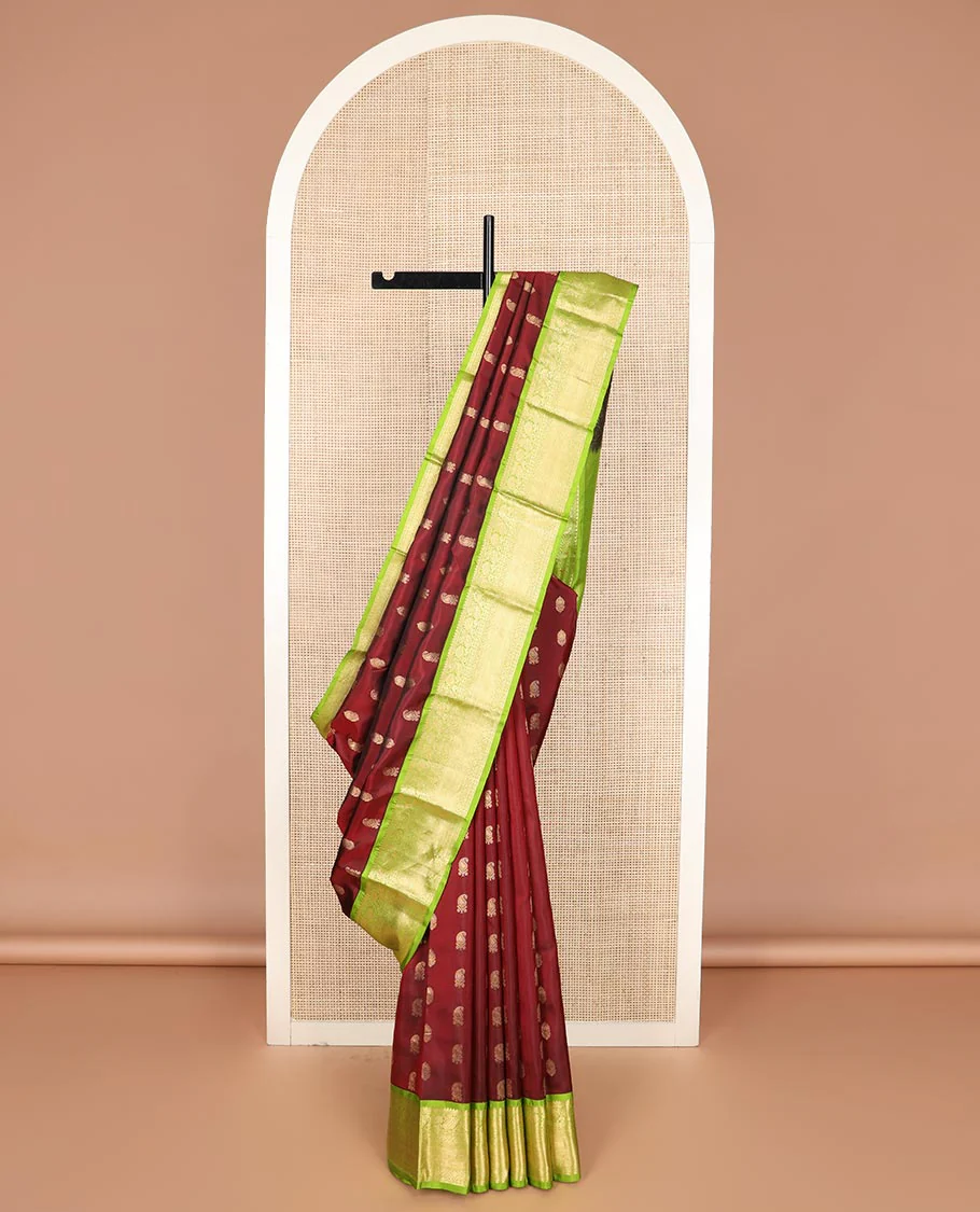 Maroon zari buttas Vasundhara silk saree, contrast border of rekku, muthu, banaras, manga, kamalam, diamond, and vanki designs, and diagonal striped pallu