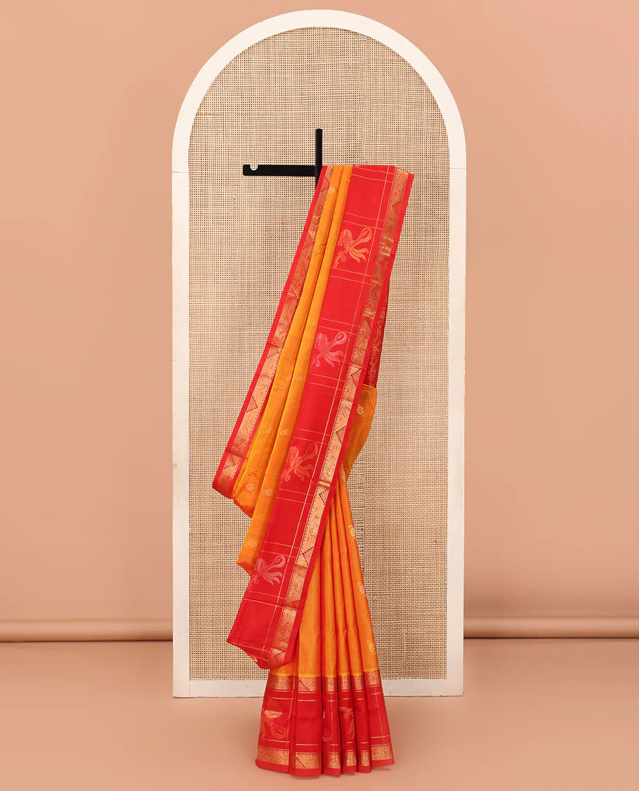 Orange Uppada Silk Saree Highlighted with Floral Buttas, Captivating Contrast Border of Traditional Zari Motifs and Peacock Motifs, Pallu Depicting Floral Jaal Design, and Paired with a Contrast Zari-Bordered Blouse