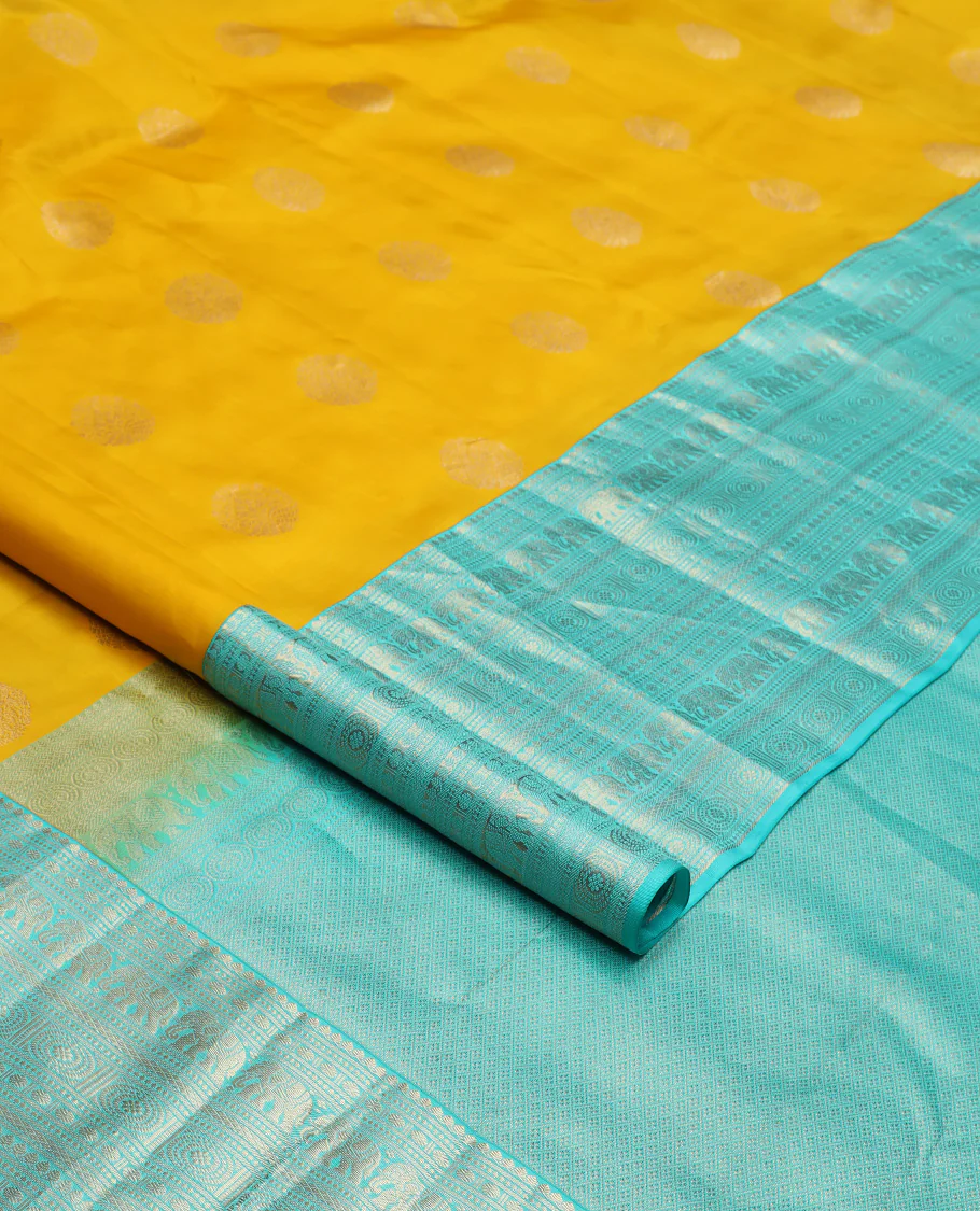 Yellow zari buttas Vasundhara silk saree, contrast border of thilakam mokku, poun, yaanai, chakram, and mayil kann designs, and jaal pallu