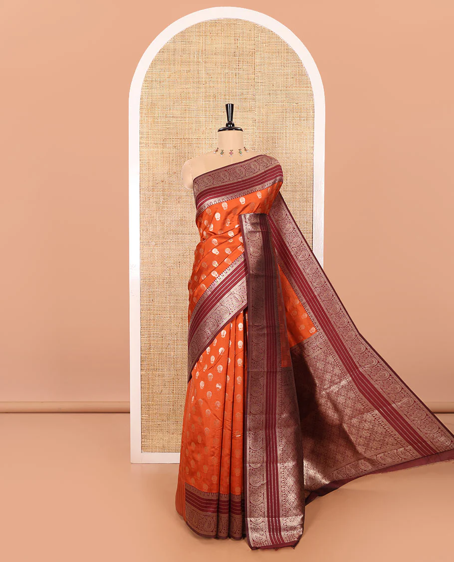 Rust Orange Kanchi Silk Saree Gracefully Embellished with Zari Buttas Woven All Over Its Body, Highlighted with a Contrast Traditional Zari Border of Paisleys, Artfully Detailed Pallu of Intricate Designs, and Paired with a Contrast Zari Design Blouse