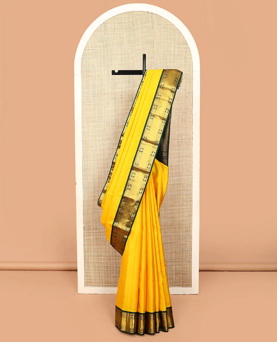 Yellow zari buttas Vasundhara silk saree, contrast border of rekku, chakram, diamond, and mayil kann designs, and geometric patterned pallu